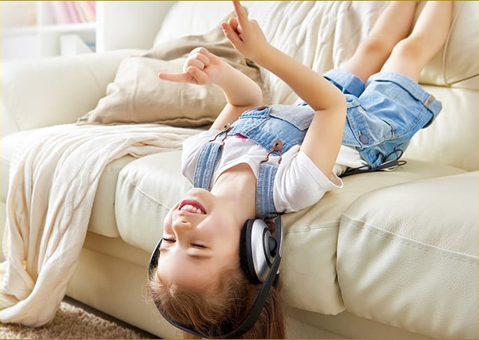 Happy boy upside down on couch, enjoying headphones